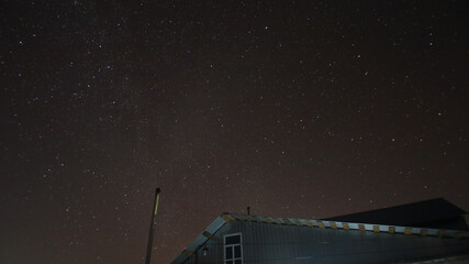 starry sky over the roof of a village house