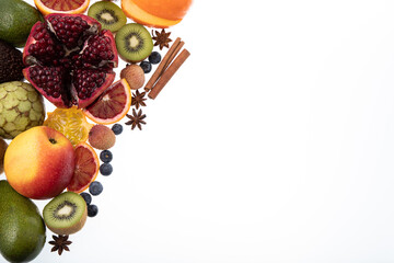 Selection of sliced fresh fruits with kiwis, pomegranate, blood orange and cinnamon on white background with free text space