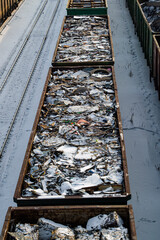 Two railway cars are filled with scrap metal. They stand on the railway tracks.