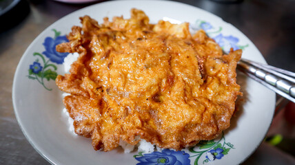 Oily omelette Thai style top on steamed Jasmine rice. Easy and popular dish in Thailand.