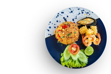 Top view Tom Yum Fried Rice with prawns and clams and green vegetables on the side on a unique blue plate , isolated on white background with copy space
