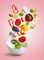 Fresh mixed vegetables falling into a bowl of salad