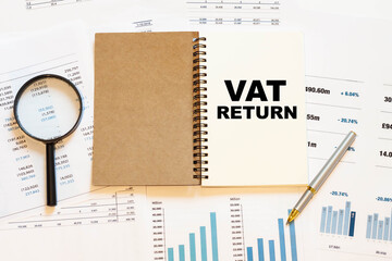 VAT RETURN - financial text on the first page of a notebook, against a background of numbers and charts