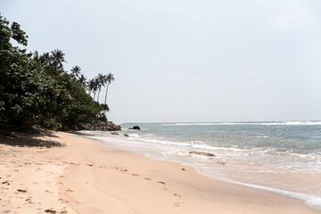 Tropikalna plaża, jasny piasek i piękny ocean oraz palmy.