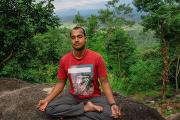 man meditating at rock in deep green forests for spiritual enlightenment