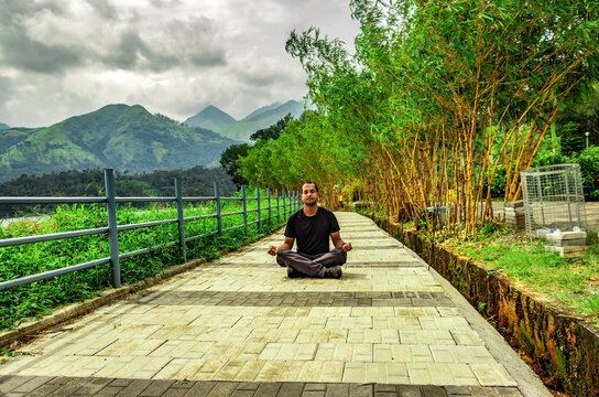 man meditating at beautiful lake hiking trails with mountain background from unique perspective