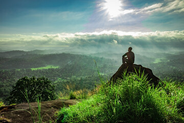 man backlight watching the amazing view of mountain covered with white mist at dawn