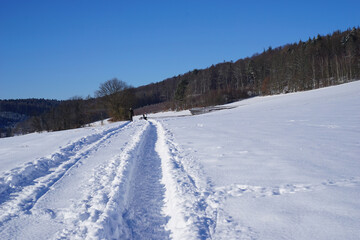 Fototapeta na wymiar Traktorspuren im hohen Schnee als Spuren zum Wandern oder Spazierengehen 