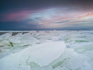 Fototapeta na wymiar blocks of ice on the coast of sea at sunset. artic winter landscape