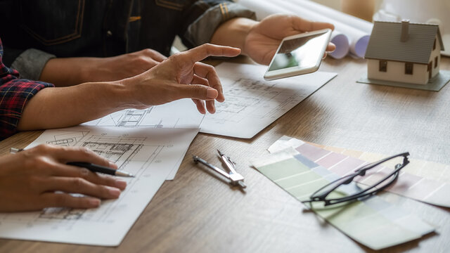 Interior designer and Architect choosing color in color swatch samples chart for house coloring selection in office with blueprint. Construction concept.