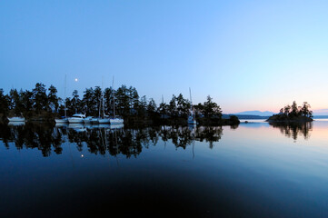 Moonrise over calm waters and boats in Princess Bay, Wallace Island, Gulf Islands, British...
