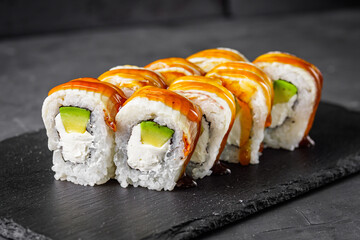 appetizing Philadelphia sushi roll with eel and avocado on a black stone plate