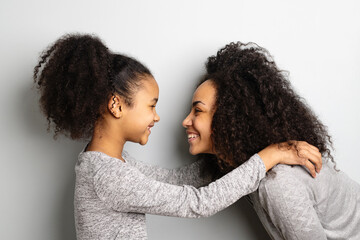 African american mother with her daughter looking and smiling at each other. - obrazy, fototapety, plakaty