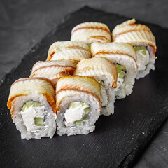 appetizing Philadelphia sushi roll with eel and cucumber on a black stone plate