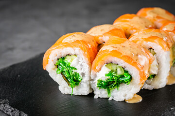 appetizing sushi roll philadelphia with salmon cucumber and chuka on a black stone plate
