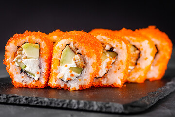 appetizing sushi roll california with eel cheese cucumber avocado and caviar masago on a black stone plate