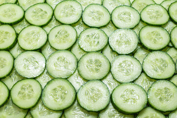 Fresh green slices of cucumber as background.