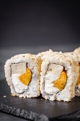 appetizing sushi roll california with tofu cheese and omelet on a black stone plate