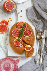 Sponge cake with red oranges on gray background