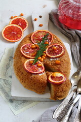 Sponge cake with red oranges on gray background