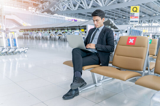 Caucasian Business Man Is Working With Laptop Computer And Keep Distance From Another Passenger. New Normal And Social Distancing Concept In Airport. .