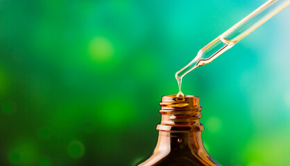 Fototapeta na wymiar A drop of oil drips into a jar on a green background.