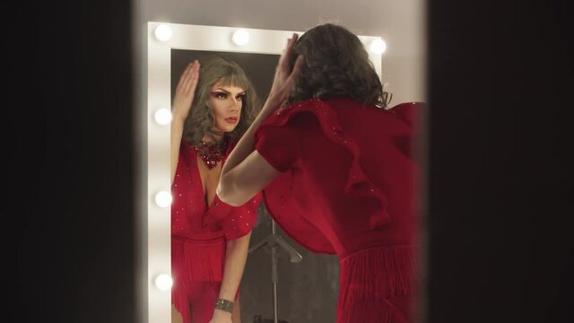 A young man drag artist preening up in front of the mirror 