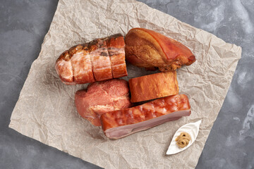 On the parchment is a variety of smoked pork. View from above. Assorted semi-finished meat products.