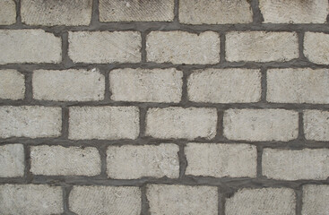 The wall is made of white, large brick. Texture.