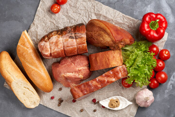 Variety of smoked pork with baguette and cherry tomatoes. top View