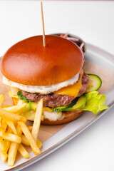 Vertical photo of menu with beef burger with sauce and fries potatoes over white table.