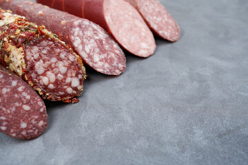 Assortment of raw smoked sausages on a gray table with copy space.