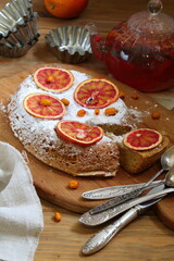 Sponge cake with red oranges on gray background