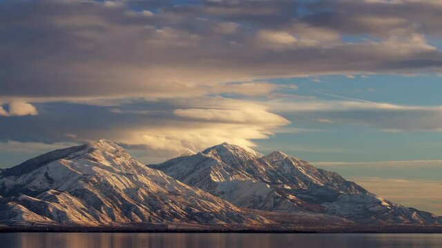 Time lapse over snowcapped mountain range looking at Mt. Nebo from over Utah Lake during sunset.