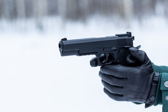 Gun in hand close-up. Black leather gloves with a pistol. Shooting in nature.