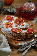 Sponge cake with red oranges on gray background