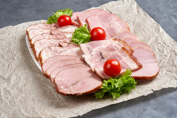 A large plate with cold cuts and herbs on wrapping paper.
