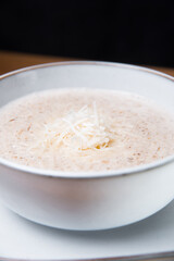 Close up photo of soup creme of mushrooms and parmesan in white bowl.