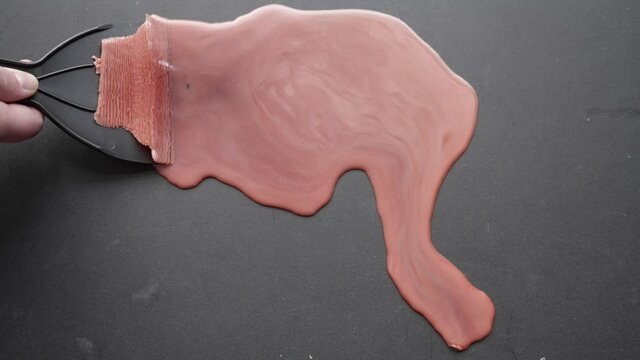 Red wax being satisfyingly scraped off a black surface.
