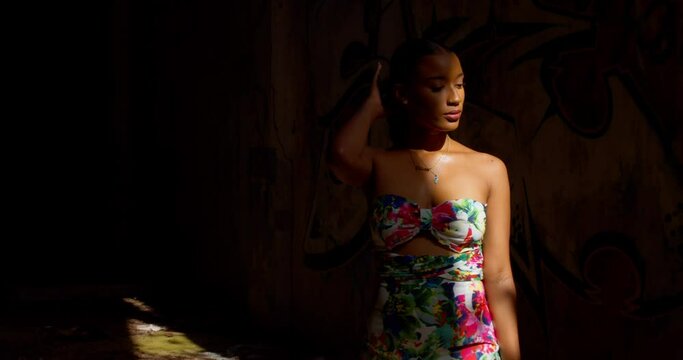 A woman walks from the light of the sun rays into the drkness of an abandoned warehouse