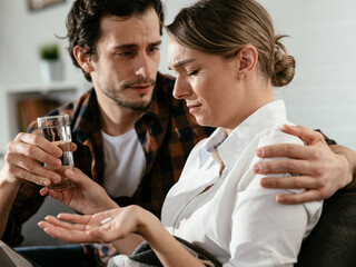 Young woman sick in bed holding glass of water..Woman drinking medicine.