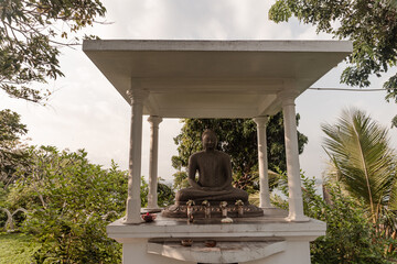 Posąg Buddy na tle zieleni w buddyjskiej świątyni.