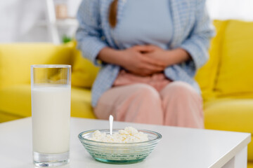 Cropped view of cottage cheese and glass of milk near woman with allergy on blurred background