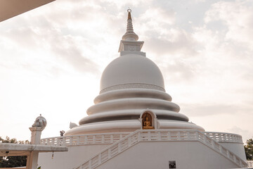 Piękna biała stupa, pagoda w świątynni buddyjskiej na tle nieba i zachodzącego słońca.