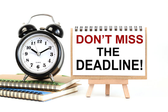 don't miss the deadline. text on white notepad paper on a stand next to our desk clock on a sideboard. on white background