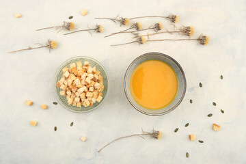Pumpkin cream soup and  bread croutons, top view. Autumn or winter pumpkin soup on table with dried flowers.