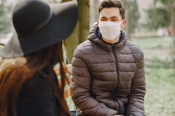 People in the city. Persons in a masks. Coronavirus theme. Couple sitting on a bench.