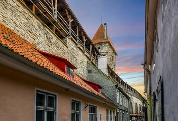 The ancient defensive city wall and Tower behind Monks of the medieval city of Tallinn, Estonia, at twilight, on the coast of the Baltic Sea