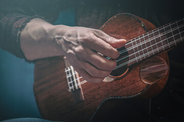 Hands of a man playing the ukulele. Folk music performer on ukulele. Photo with toning and shallow...