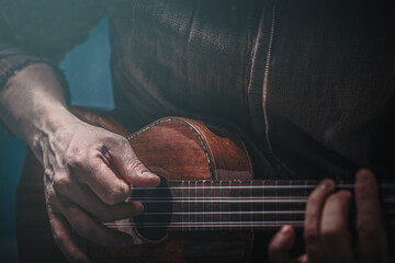 Hands of a man playing the ukulele. Folk music performer on ukulele. Photo with toning and shallow...